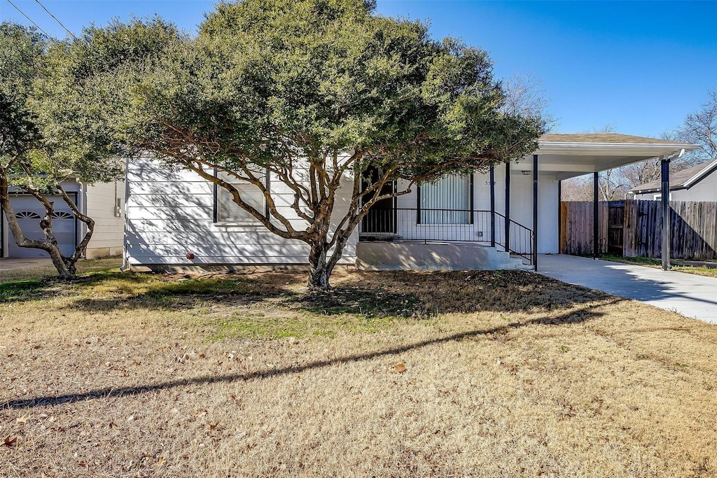 view of front facade featuring a carport, covered porch, and a front lawn