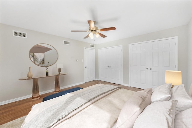 bedroom with ceiling fan, multiple closets, and light wood-type flooring