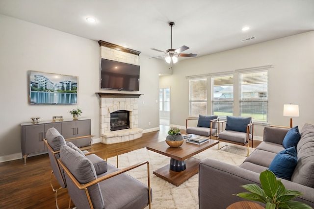 living room featuring ceiling fan, a stone fireplace, and light hardwood / wood-style floors