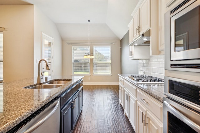 kitchen featuring sink, appliances with stainless steel finishes, hanging light fixtures, light stone counters, and white cabinets