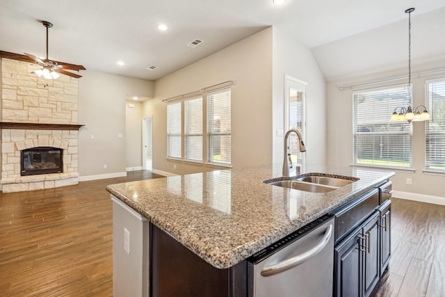 kitchen with decorative light fixtures, dishwasher, an island with sink, sink, and dark hardwood / wood-style flooring