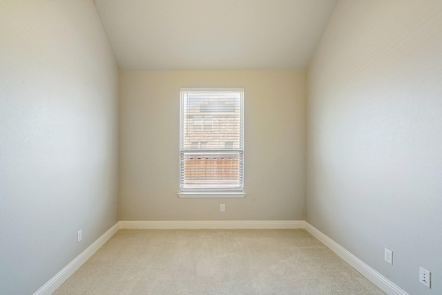 carpeted empty room featuring lofted ceiling