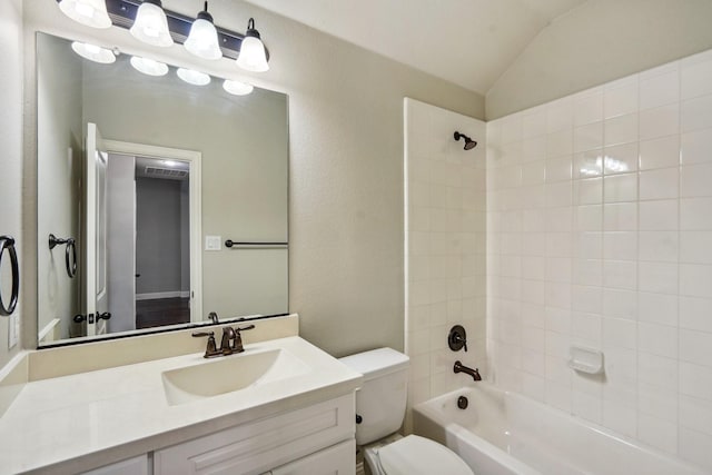 full bathroom featuring tiled shower / bath, vaulted ceiling, vanity, and toilet