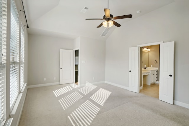 unfurnished bedroom with ensuite bathroom, light carpet, ceiling fan, and high vaulted ceiling