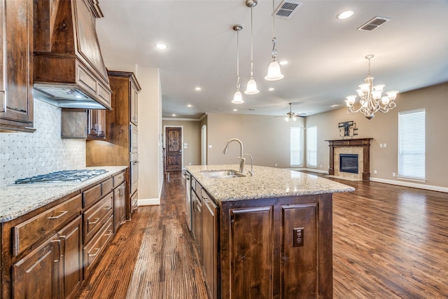 kitchen with visible vents, stainless steel gas cooktop, a sink, premium range hood, and dark wood-type flooring