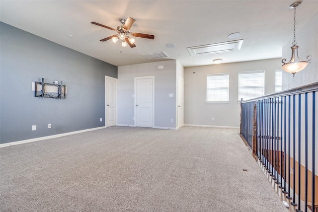 unfurnished room with visible vents, ceiling fan, light colored carpet, and attic access