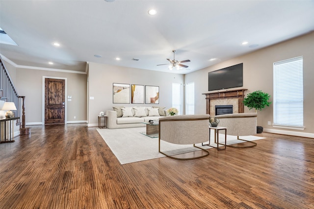 living area with recessed lighting, stairs, wood finished floors, and a glass covered fireplace