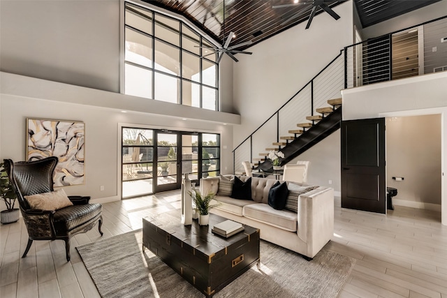 living room with a high ceiling, light wood-type flooring, ceiling fan, and french doors