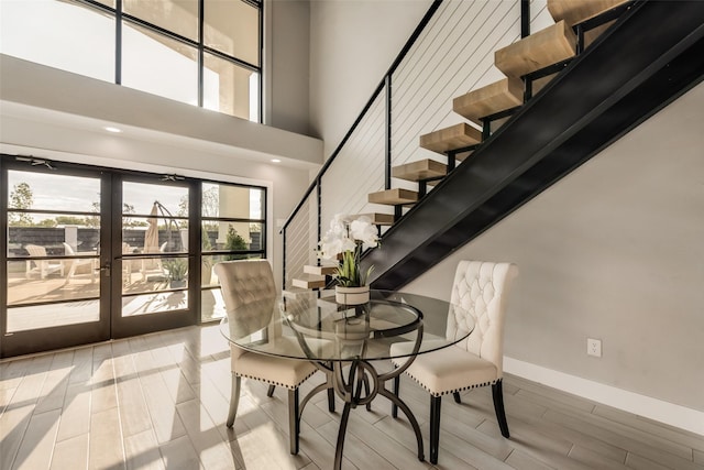 dining area featuring light hardwood / wood-style flooring, french doors, and a high ceiling