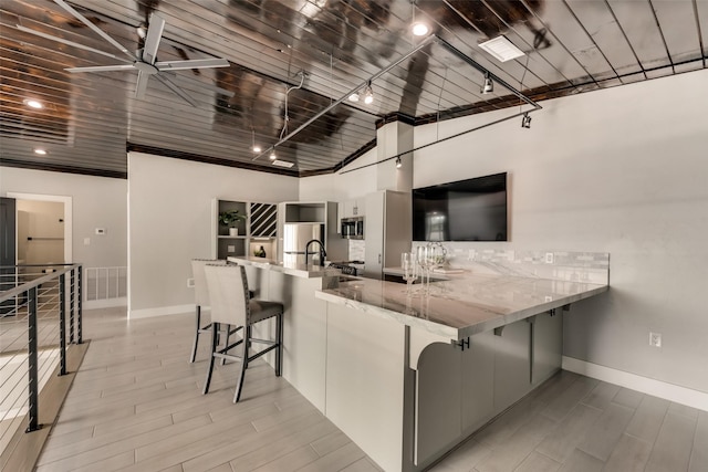 kitchen with white cabinetry, a kitchen breakfast bar, kitchen peninsula, and appliances with stainless steel finishes