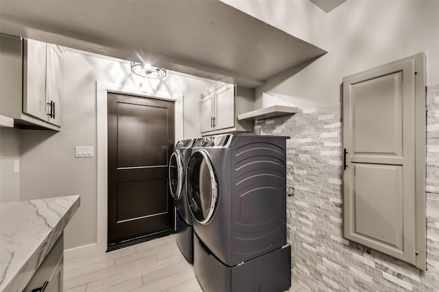 laundry room with cabinets, light hardwood / wood-style flooring, and washer and dryer