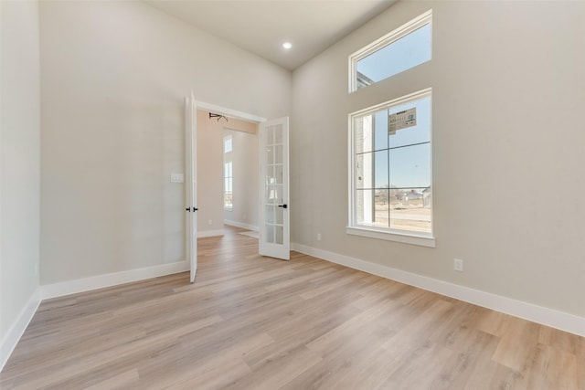 unfurnished room with french doors, a healthy amount of sunlight, and light hardwood / wood-style flooring