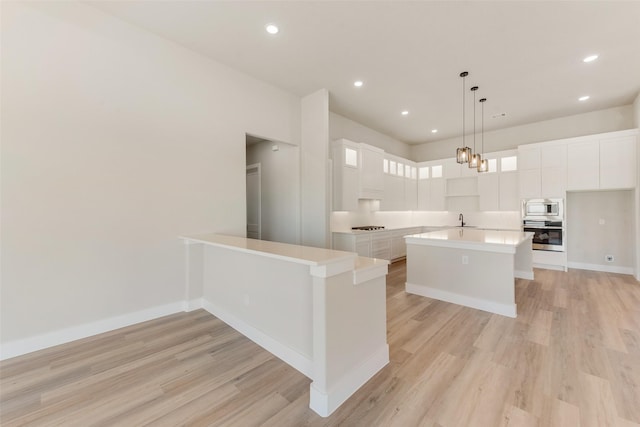 kitchen featuring sink, appliances with stainless steel finishes, a kitchen island, pendant lighting, and white cabinets