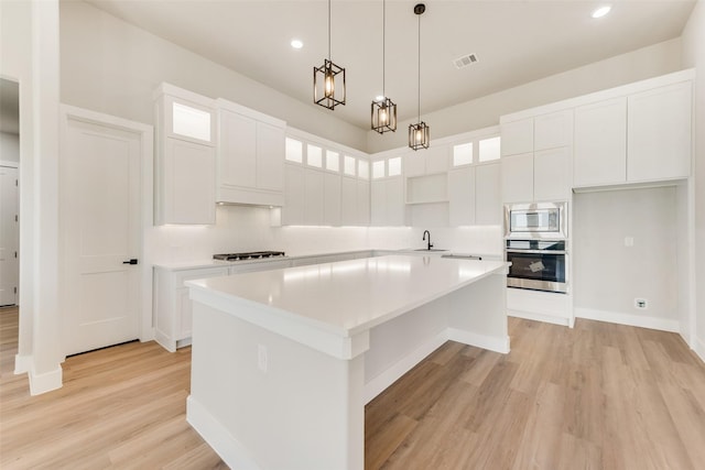 kitchen featuring tasteful backsplash, light hardwood / wood-style flooring, a kitchen island, stainless steel appliances, and white cabinets