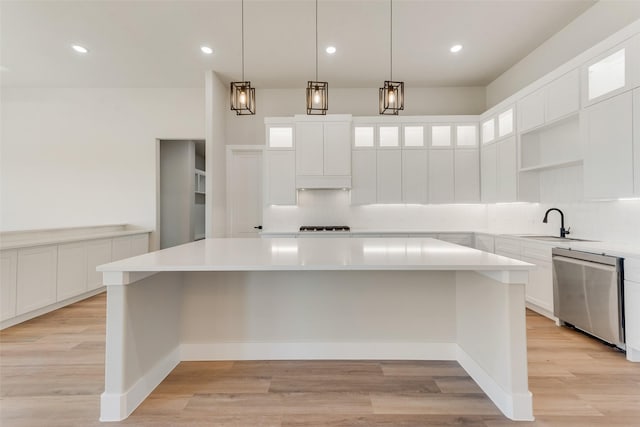 kitchen with pendant lighting, stainless steel dishwasher, a center island, and white cabinets