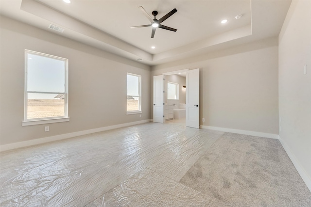 unfurnished bedroom with ensuite bathroom and a tray ceiling