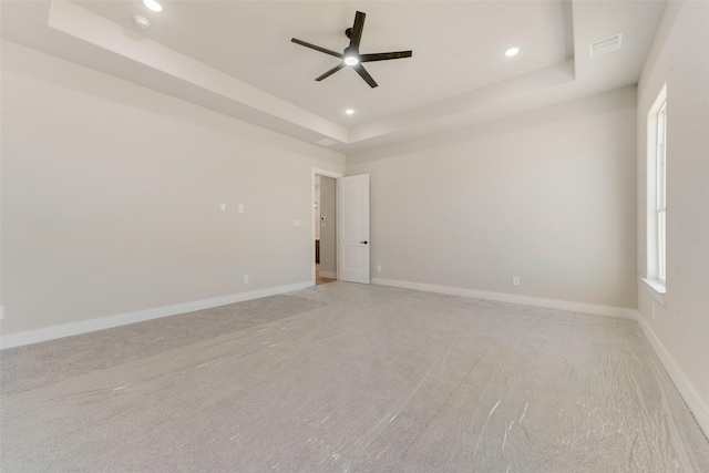 carpeted spare room featuring ceiling fan and a raised ceiling