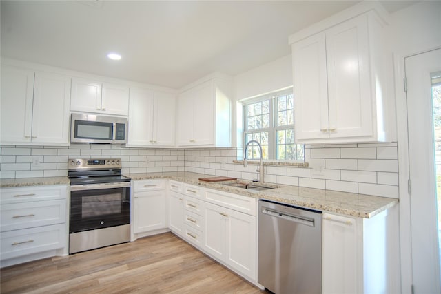 kitchen with appliances with stainless steel finishes, sink, decorative backsplash, and white cabinets