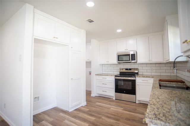 kitchen with white cabinetry, sink, light stone counters, stainless steel appliances, and light hardwood / wood-style flooring