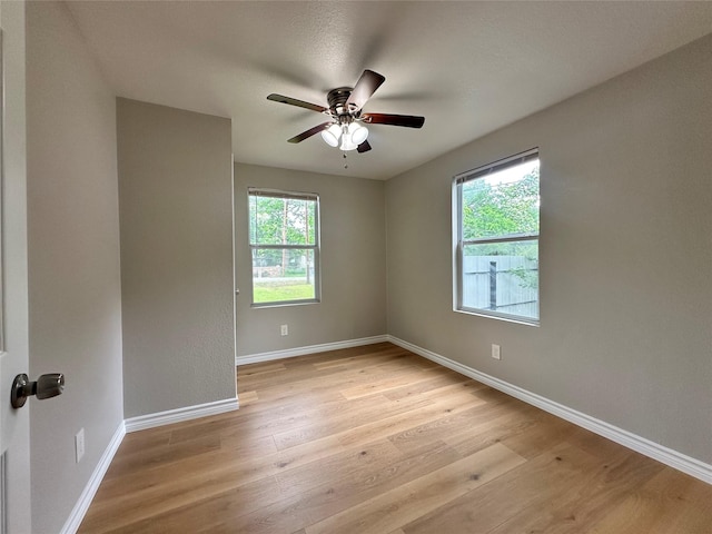 empty room featuring ceiling fan, plenty of natural light, and light hardwood / wood-style floors