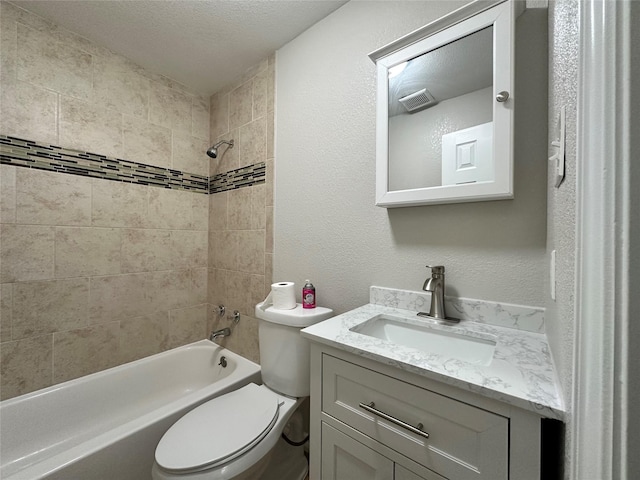 full bathroom featuring vanity, toilet, a textured ceiling, and tiled shower / bath