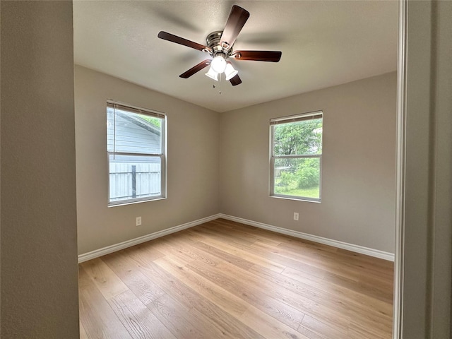 empty room featuring plenty of natural light, ceiling fan, and light hardwood / wood-style flooring