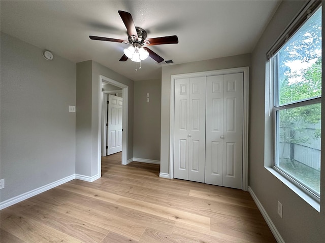 unfurnished bedroom featuring ceiling fan, light wood-type flooring, and a closet