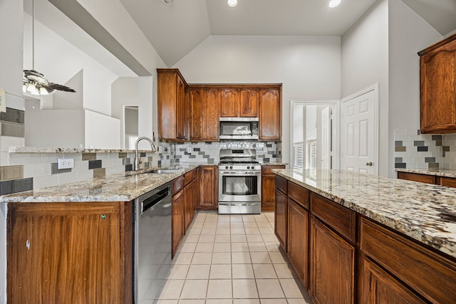 kitchen featuring appliances with stainless steel finishes, lofted ceiling, sink, light tile patterned floors, and light stone countertops