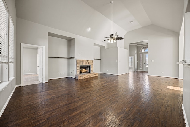 unfurnished living room with a brick fireplace, dark hardwood / wood-style floors, high vaulted ceiling, and ceiling fan