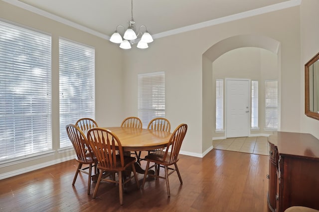 dining area with wood-type flooring, ornamental molding, and a notable chandelier