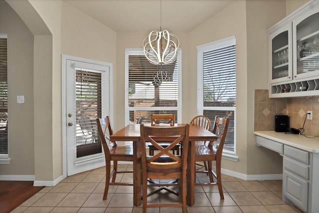 dining area featuring a notable chandelier, built in desk, and light tile patterned flooring