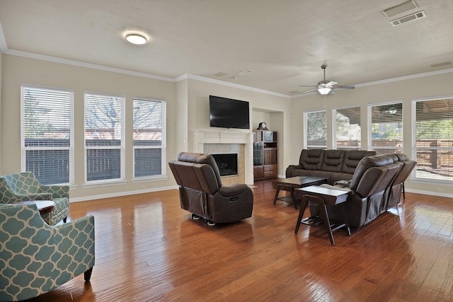 living room with hardwood / wood-style flooring, ornamental molding, a healthy amount of sunlight, and a tile fireplace