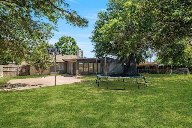 view of yard with a trampoline, a sunroom, and a patio