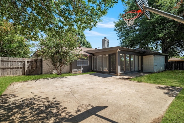 back of property with a sunroom and a lawn