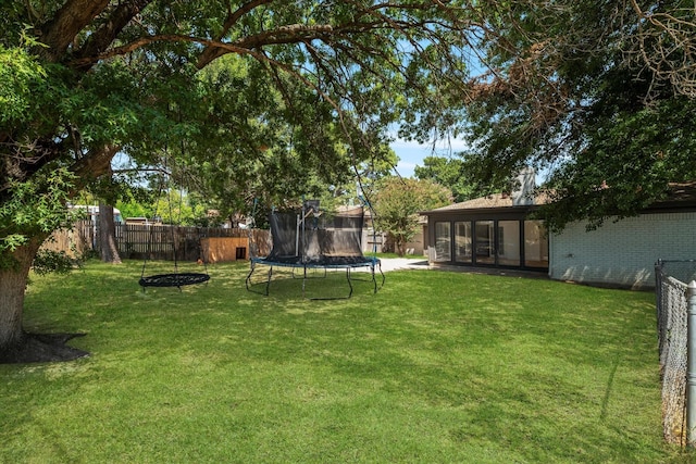 view of yard featuring a trampoline and a sunroom