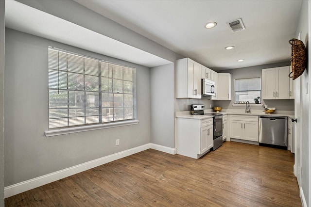 kitchen featuring white cabinetry, sink, light hardwood / wood-style flooring, and appliances with stainless steel finishes