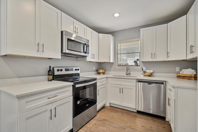 kitchen with sink, light hardwood / wood-style flooring, stainless steel appliances, and white cabinets