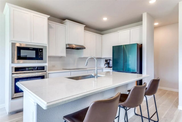 11416 Silver Queen Dr, Aubrey, TX 76227 - kitchen with sink, light hardwood / wood-style floors, black appliances, an island with sink, and white cabinets