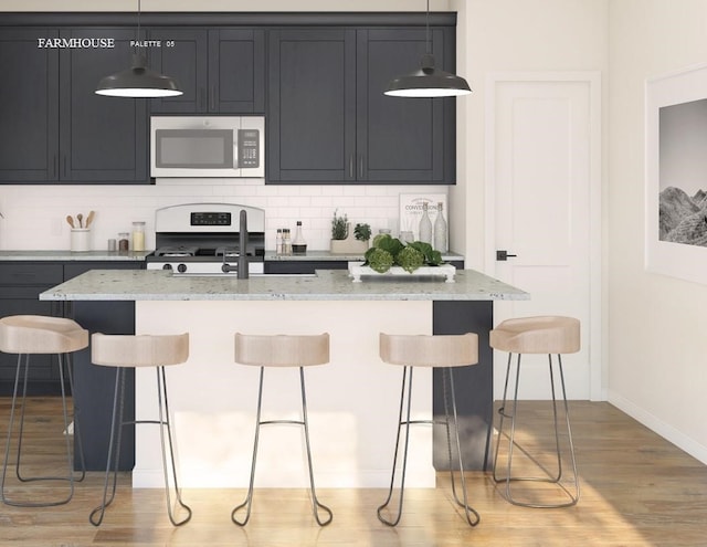 kitchen featuring appliances with stainless steel finishes, pendant lighting, an island with sink, a kitchen bar, and light stone countertops