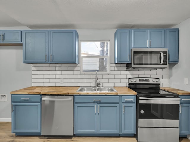 kitchen featuring wood counters, stainless steel appliances, and sink