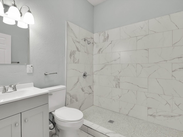 bathroom featuring vanity, toilet, and a tile shower