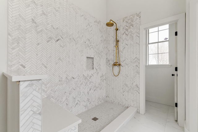 full bathroom featuring marble finish floor, baseboards, and tiled shower