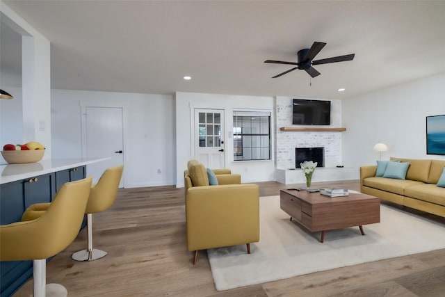 living room with a fireplace, wood finished floors, a ceiling fan, and recessed lighting