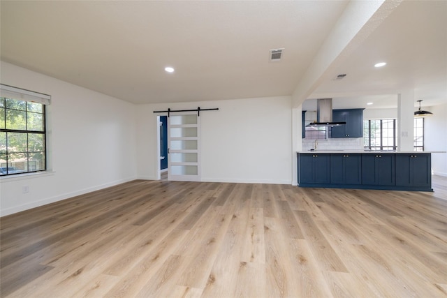 unfurnished living room featuring a barn door and light wood-type flooring