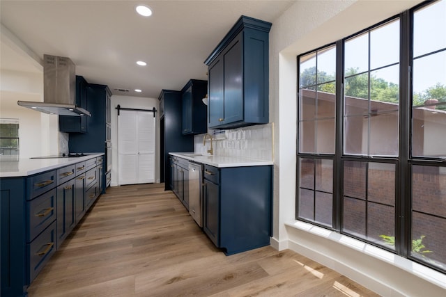 kitchen with island range hood, stainless steel appliances, a barn door, blue cabinetry, and light wood-type flooring