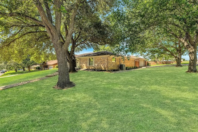 view of yard featuring a garage and central AC unit