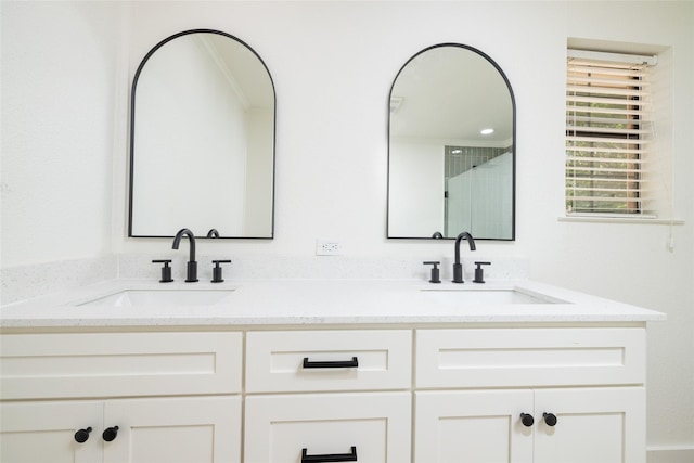 full bath with double vanity, a sink, and tiled shower