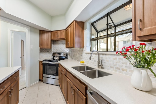 kitchen with tasteful backsplash, brown cabinetry, stainless steel appliances, light countertops, and a sink