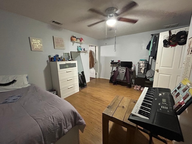 bedroom with ceiling fan, a textured ceiling, and light wood-type flooring