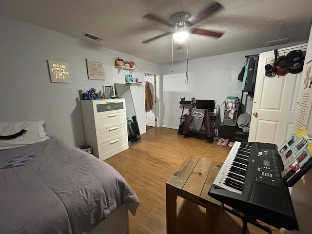 bedroom with ceiling fan, light hardwood / wood-style flooring, and a textured ceiling